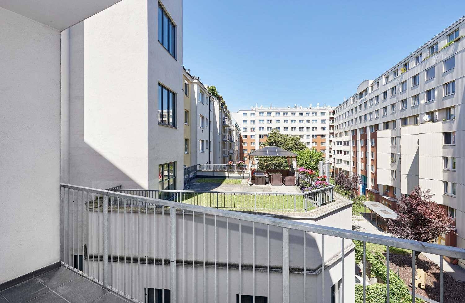 Balkon mit Blick auf einen begrünten Innenhof und die umliegenden Wohngebäude.