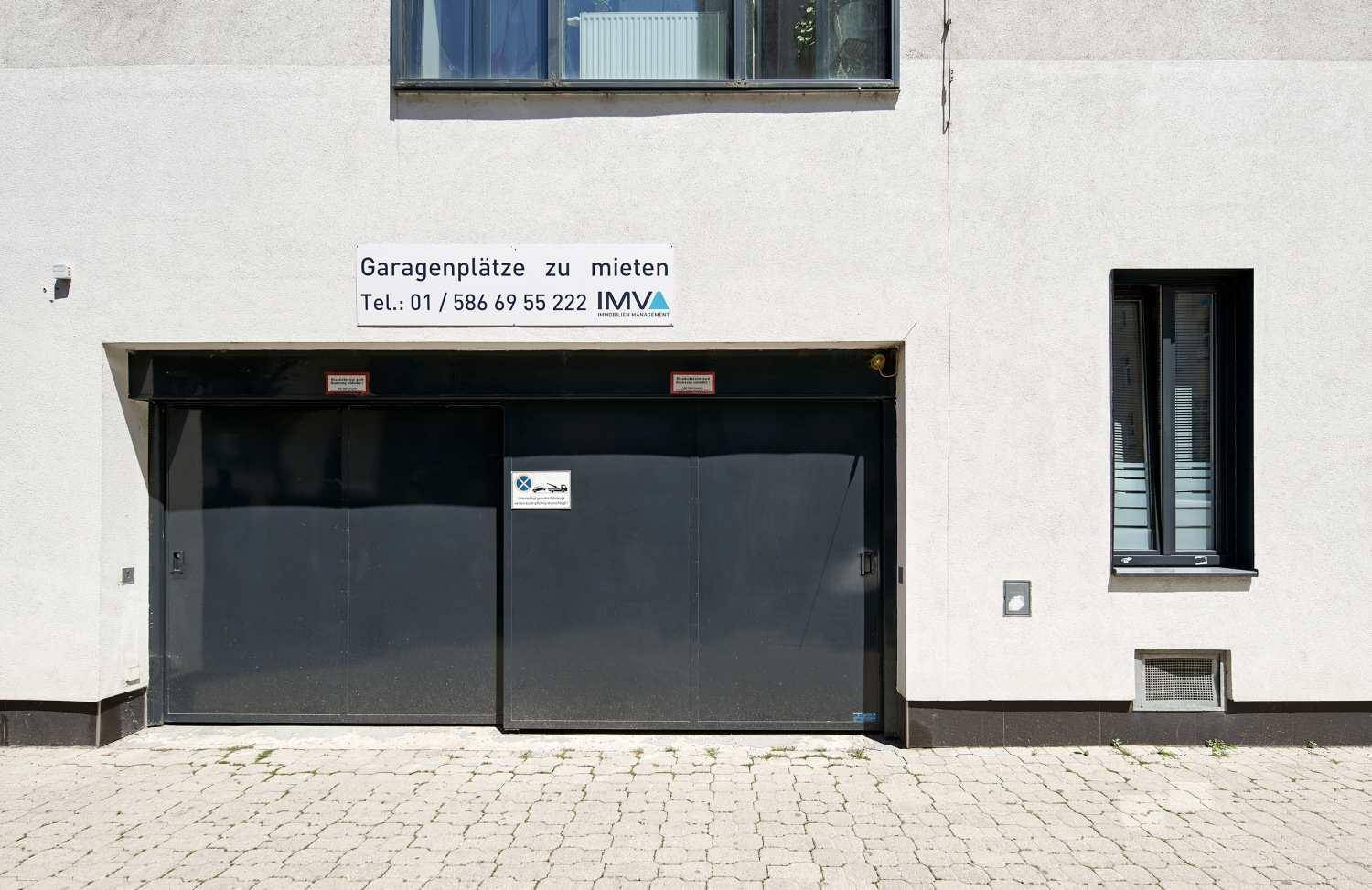 Nahaufnahme des Garagentors mit Werbeschild für Mietparkplätze.