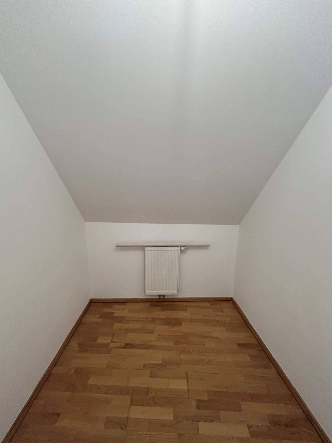 Kleiner Abstellraum mit Parkettboden, Heizung und starker Dachschräge.
