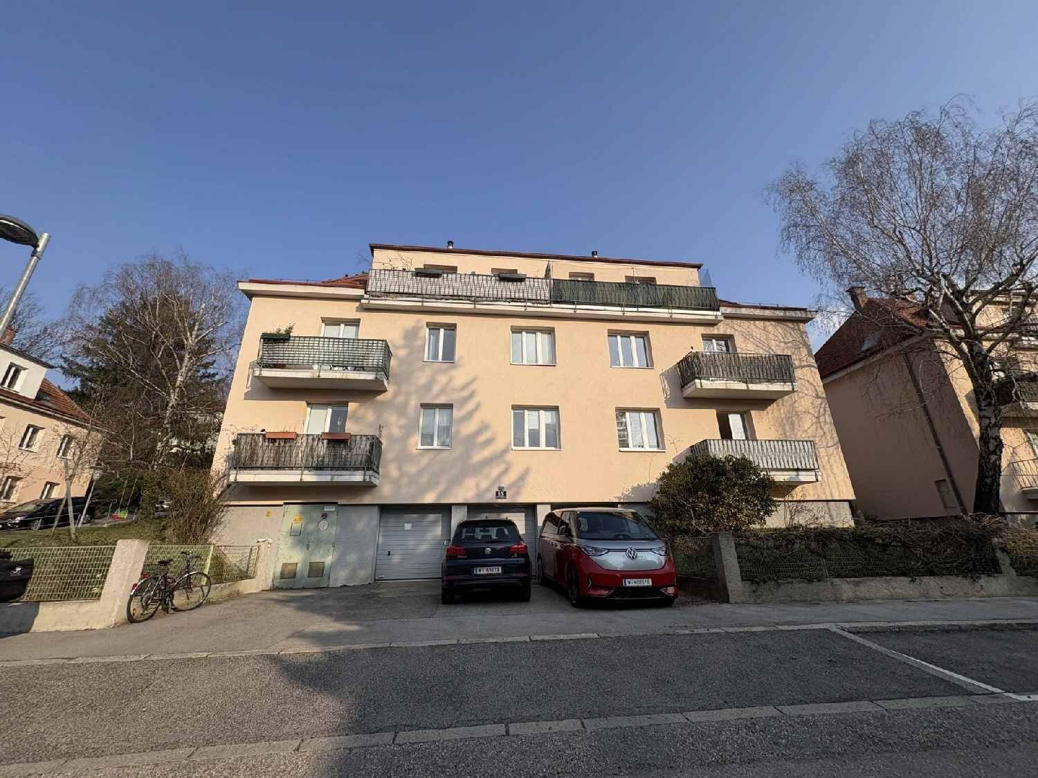 Mehrfamilienhaus mit mehreren Balkonen und Garagen im Erdgeschoss.