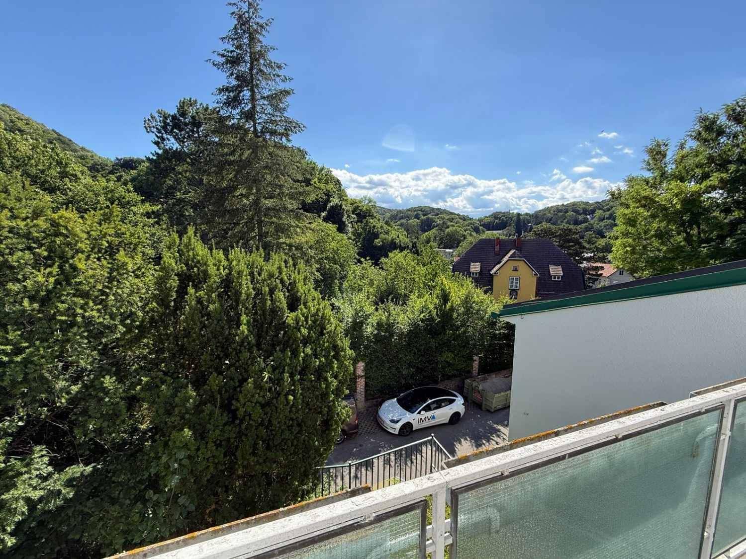 Balkon mit weitem Blick über die grüne Landschaft und die umliegenden Häuser.