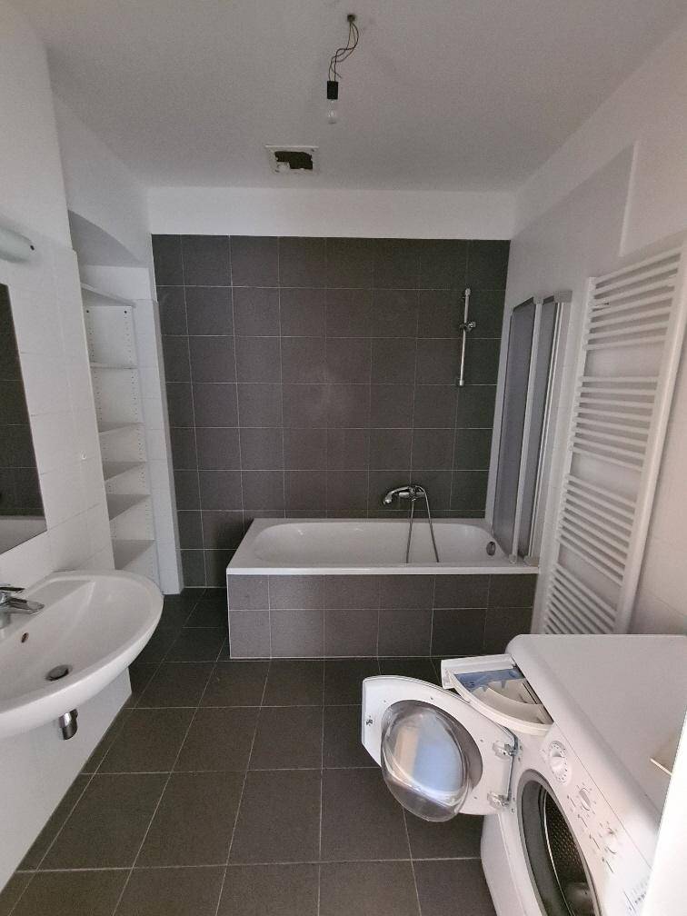 Modernes Badezimmer mit Badewanne, Waschbecken und Waschmaschine.
