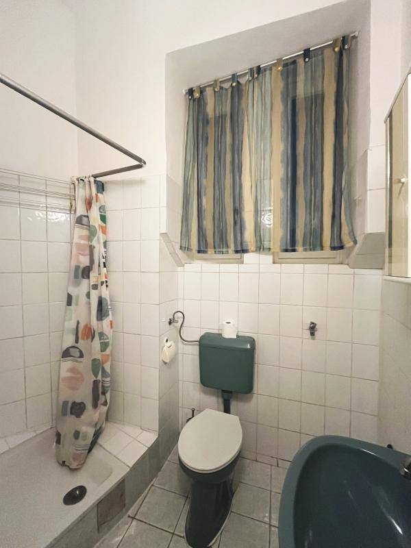 Badezimmer mit Dusche, WC und kleiner Badewanne, ausgestattet mit hellen Fliesen und Fenster.