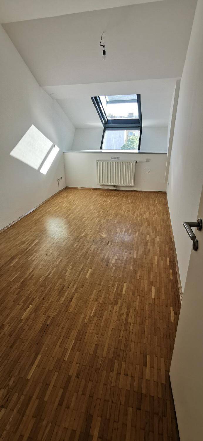 Helles Zimmer mit Holzparkett und Dachfenster, ideal als Schlafzimmer oder Arbeitsbereich.