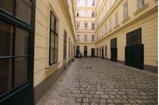 Historischer Innenhof mit Kopfsteinpflaster und hohen Gebäudefassaden, die eine ruhige Atmosphäre schaffen.