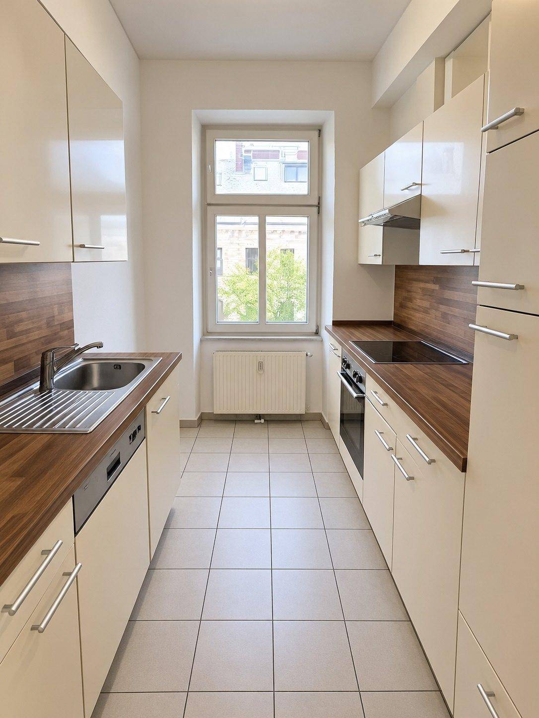 Moderne Küche mit beigen Schränken, Holzarbeitsplatten, Spüle und integrierten Geräten.