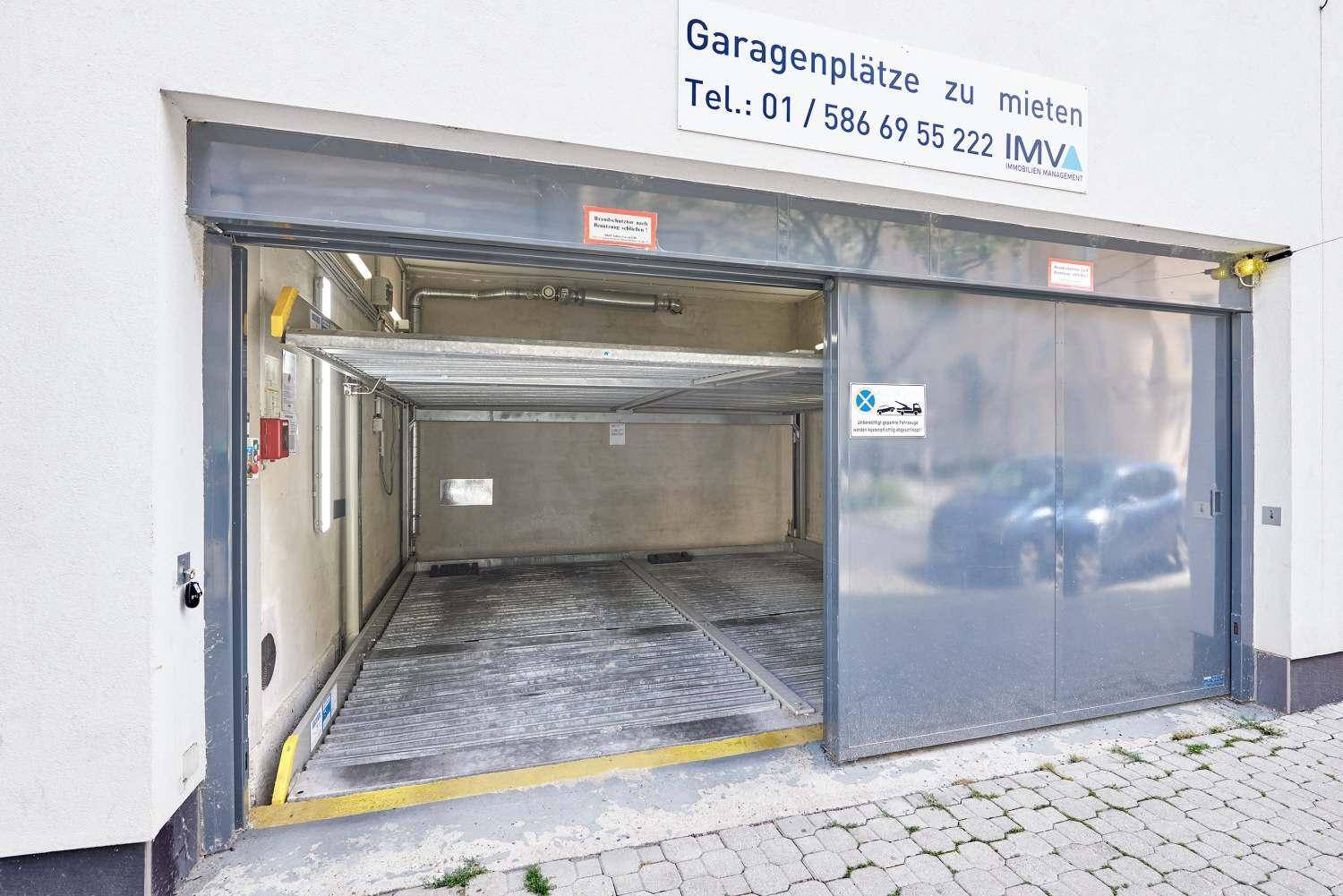 Tiefgarageneinfahrt mit automatischem Tor und Hinweisschild für Mietparkplätze.