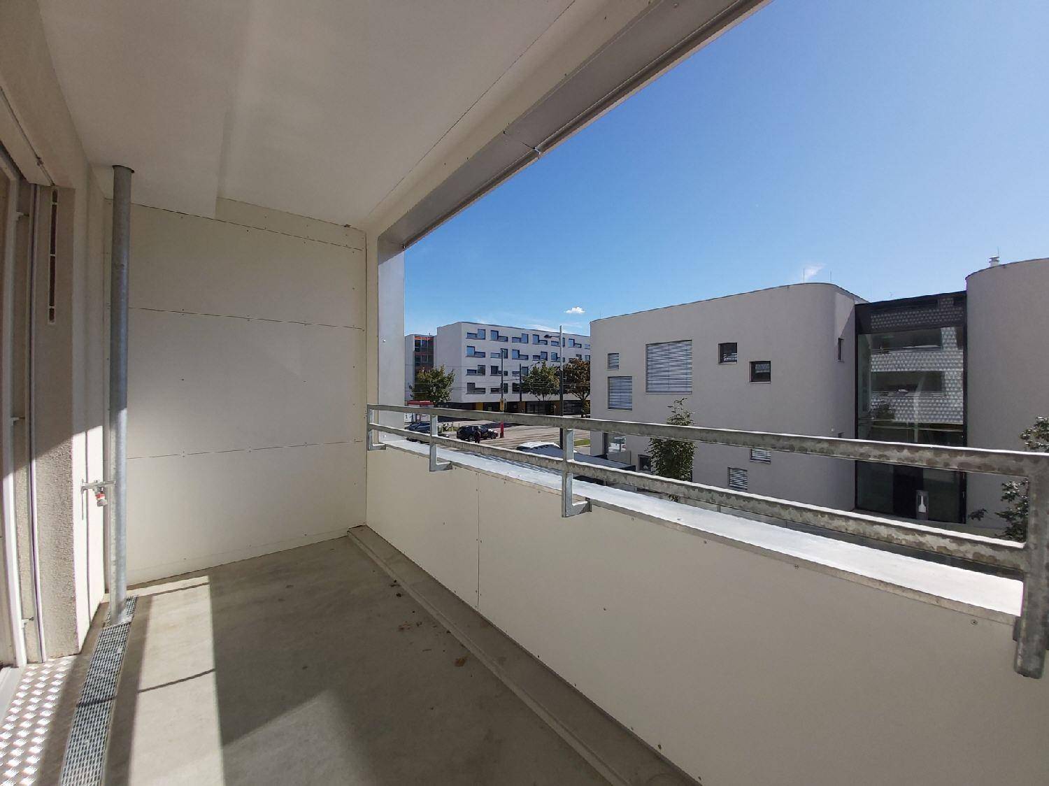 Heller Balkon mit Metallgeländer und Blick auf die umliegenden Gebäude.