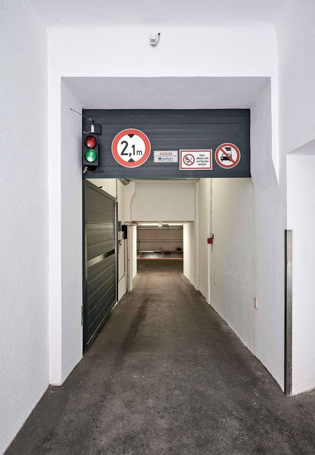 Einfahrt zu einer Tiefgarage mit Ampel und Höhenbegrenzung, die den Zugang regelt.
