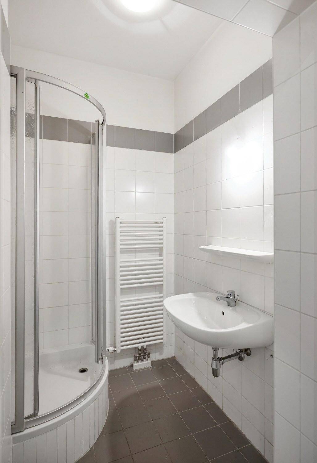 Modernes Badezimmer mit Duschkabine, Waschbecken und beheiztem Handtuchhalter.