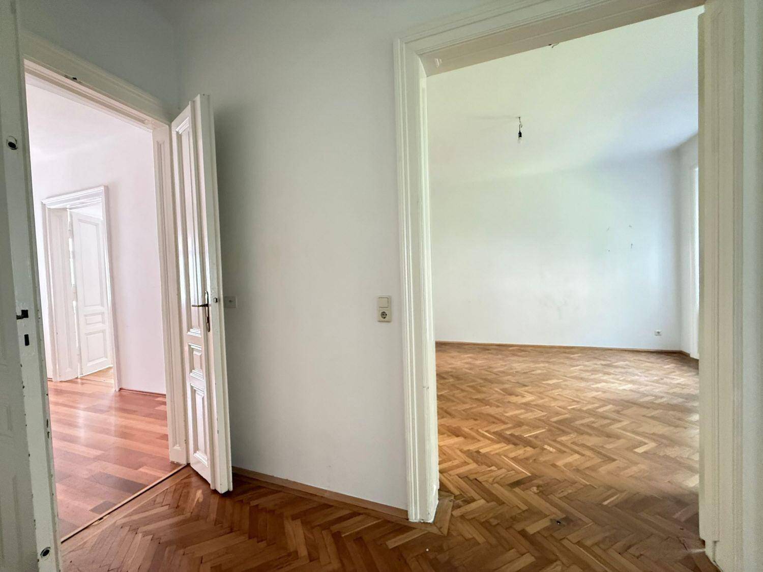 Übergang von einem Zimmer mit Fischgrätparkett in einen Flur mit Holzdielenboden.