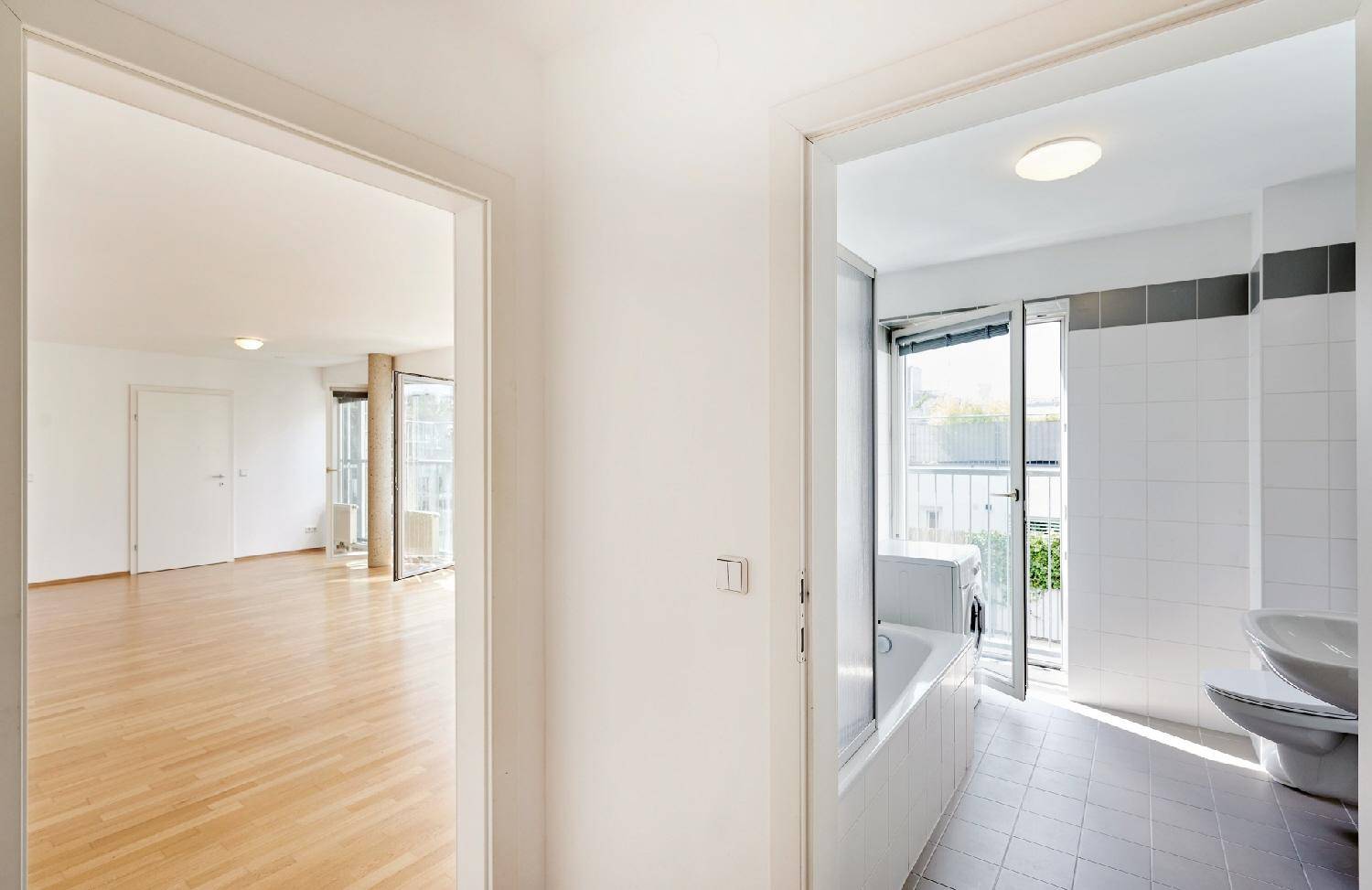 Blick durch einen Türrahmen, der den Wohnbereich und das Badezimmer miteinander verbindet.