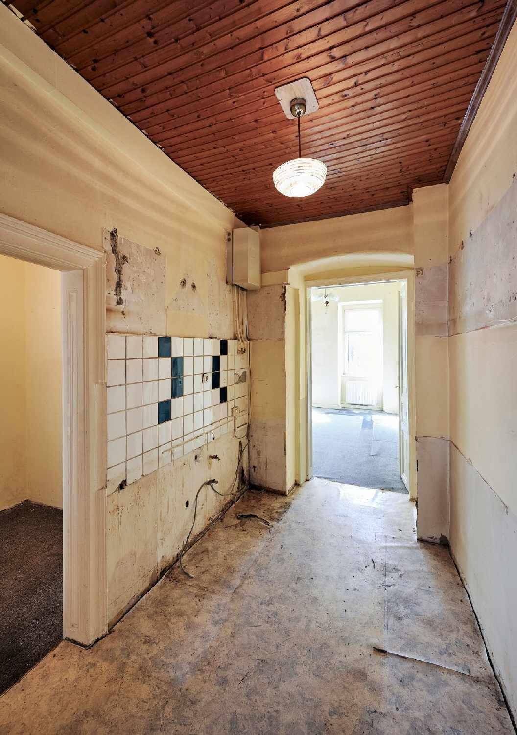 Flur mit Holzdecke und sichtbaren Spuren früherer Wandverkleidungen, die Renovierung erfordern.
