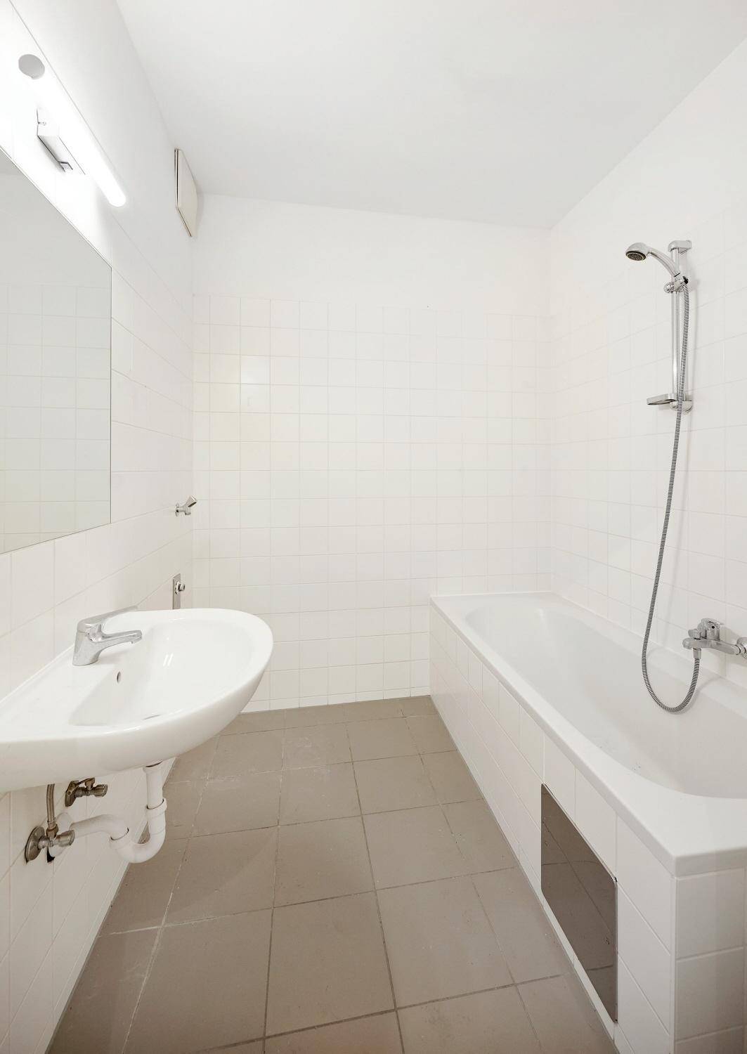 Helles Badezimmer mit Badewanne, Dusche, Einzelwaschbecken und modernen Fliesen.