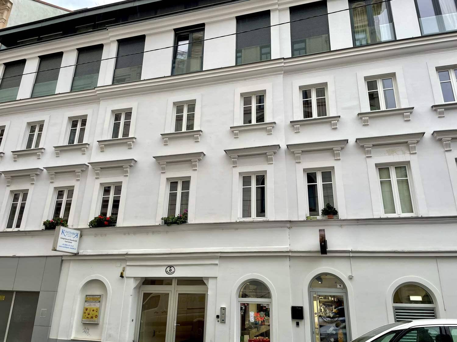 Nahaufnahme der weißen Fassade mit Fenstern und Eingangsbereich eines Stadtgebäudes.