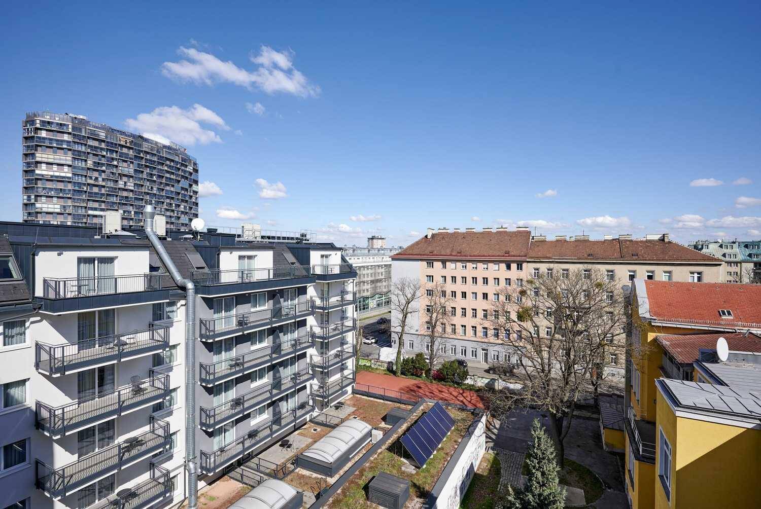 Weitläufiger Blick über eine städtische Wohngegend mit modernen Gebäuden und Grünflächen.