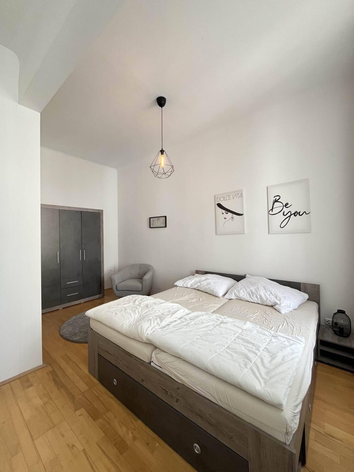 Helles Schlafzimmer mit Doppelbett, Parkettboden und einem modernen Kleiderschrank.