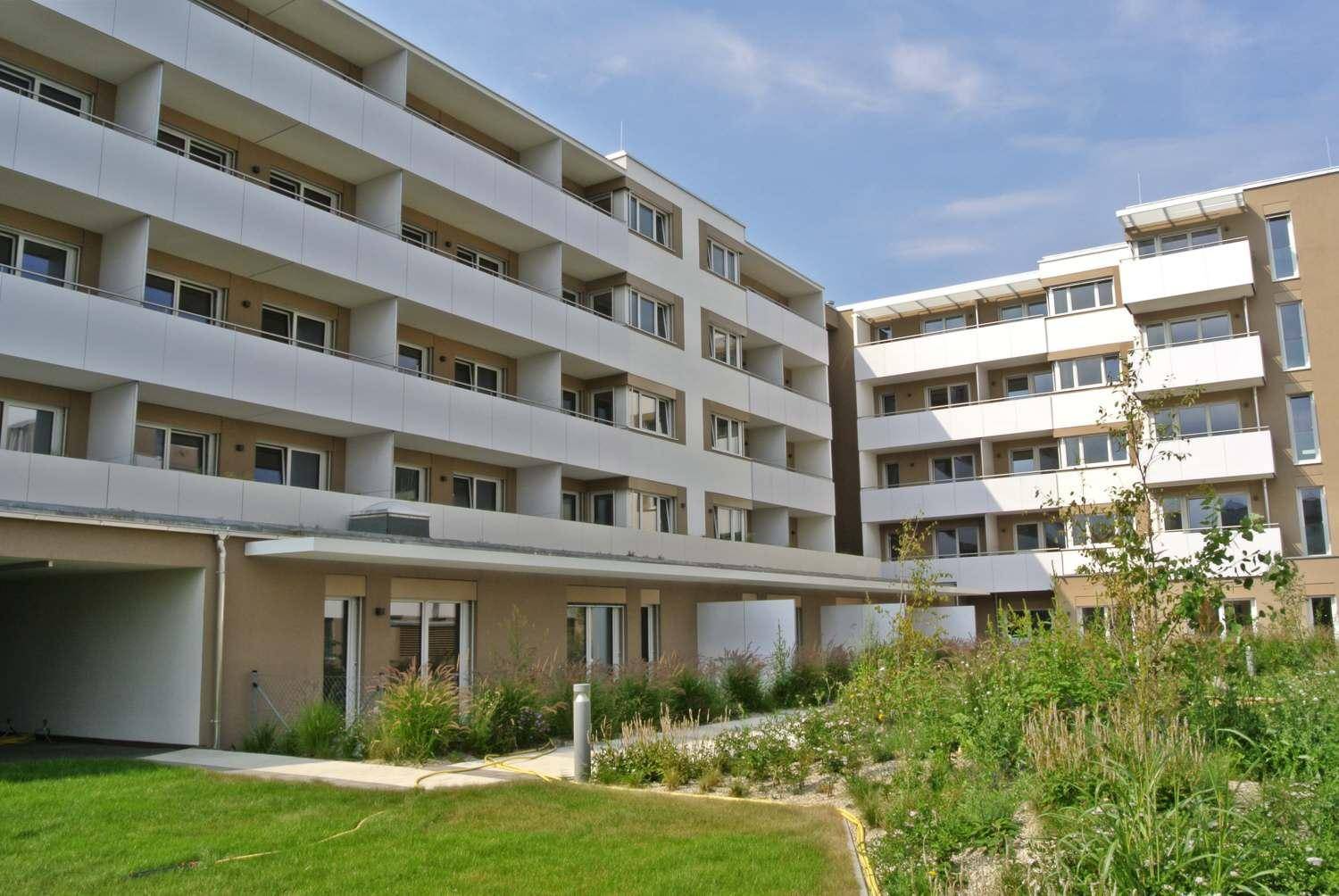 Außenansicht einer modernen Wohnanlage mit Balkonen und einem gepflegten Innenhof.