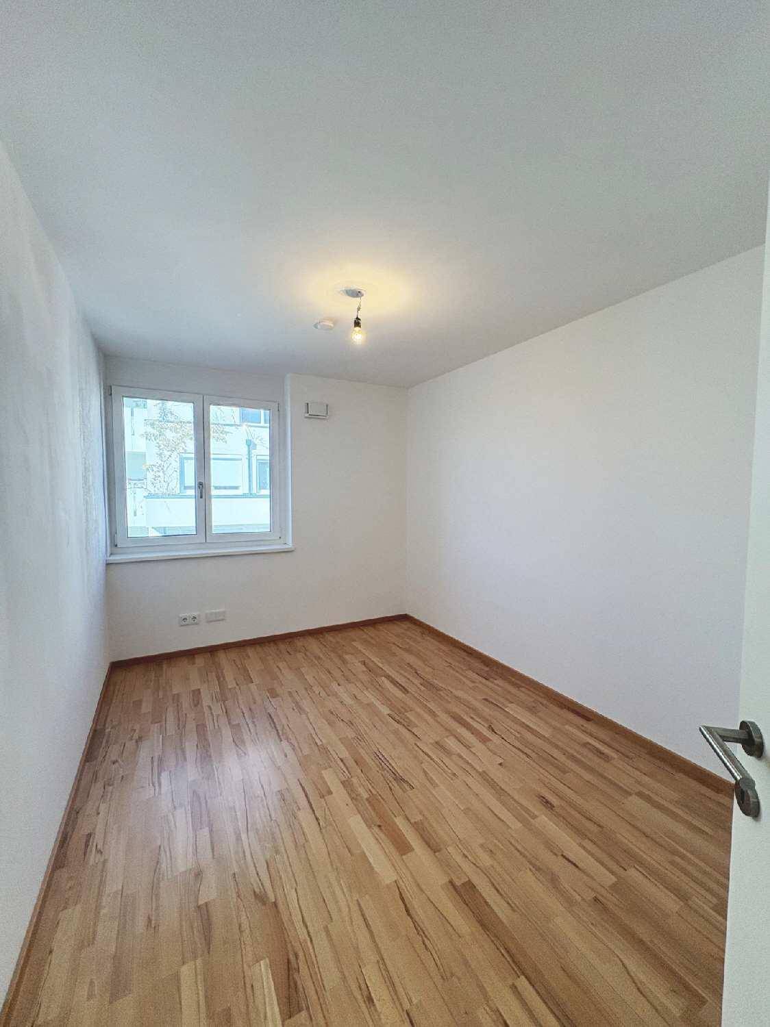 Helles Zimmer mit Holzboden und einem Fenster, bereit zur individuellen Gestaltung.