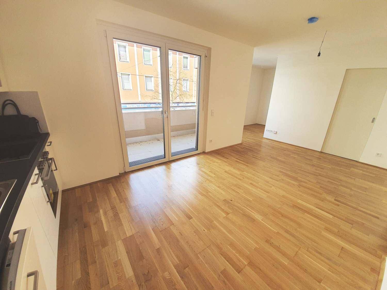 Lichtdurchfluteter Wohnbereich mit Parkettboden und großem Zugang zum Balkon.