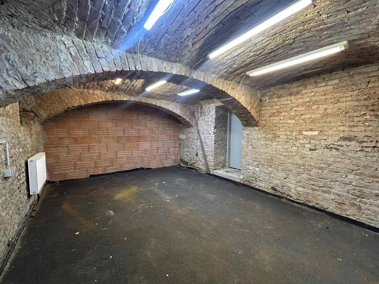Historischer Kellerraum mit freiliegenden Ziegelwänden, Gewölbedecken und einfacher Beleuchtung.