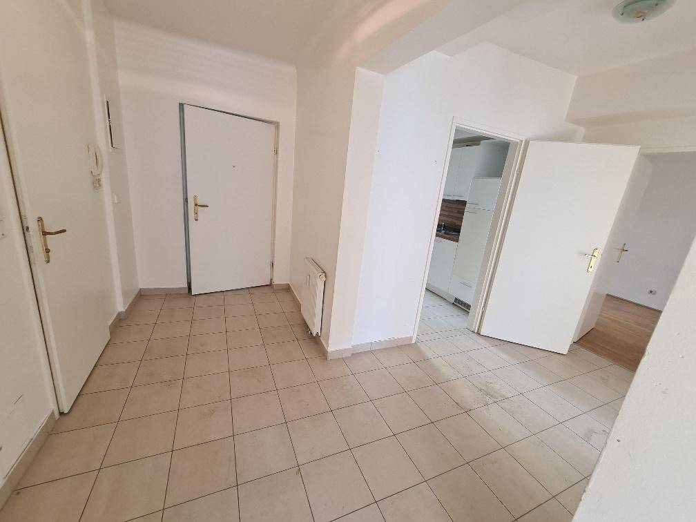 Heller Eingangsbereich mit Fliesenboden und mehreren Türen, die zu den angrenzenden Räumen führen.