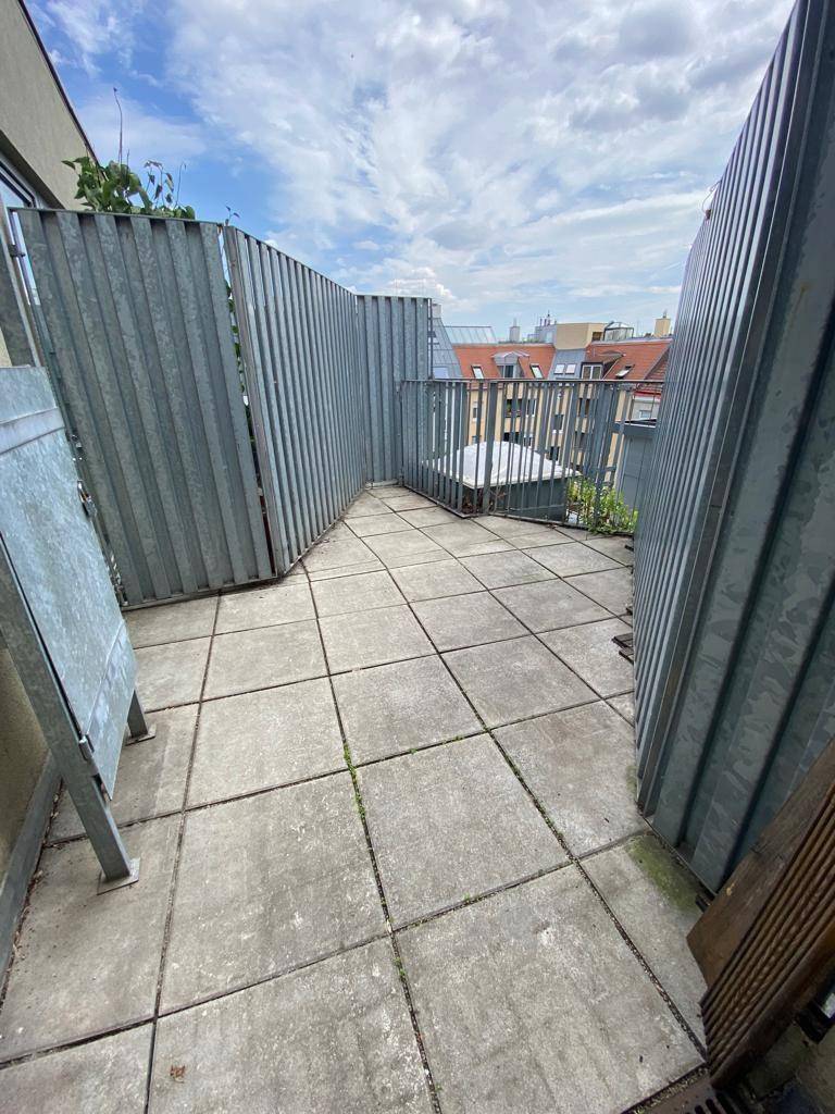Dachterrasse mit Fliesenboden und Metallabtrennungen, bietet einen weiten Blick über die Stadt.