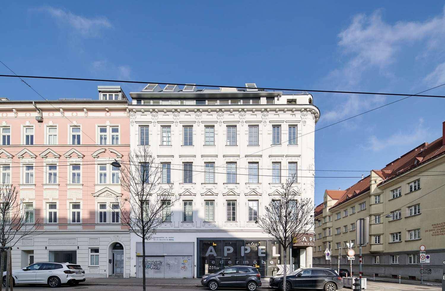 Historische Fassade eines Gebäudes mit vielen Fenstern und Geschäften im Erdgeschoss.