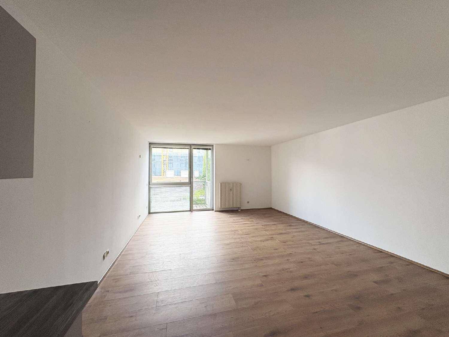 Heller Wohnbereich mit großen Fenstern und Zugang zum Außenbereich, ausgestattet mit Laminatboden.