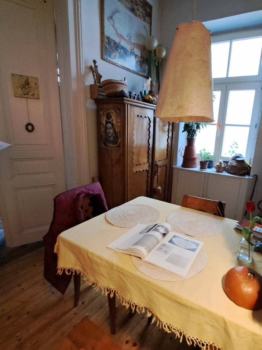 Essbereich mit Holzboden, einem Holztisch und einem großen Schrank mit Dekoration, hell und freundlich.