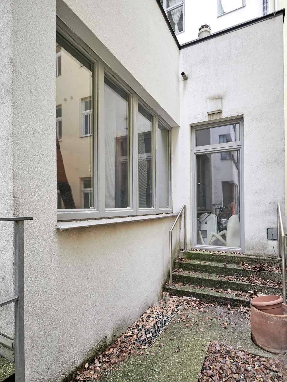 Kleiner Innenhof mit Treppe und Fenstern, der als Lichtschacht oder Zugang dient.