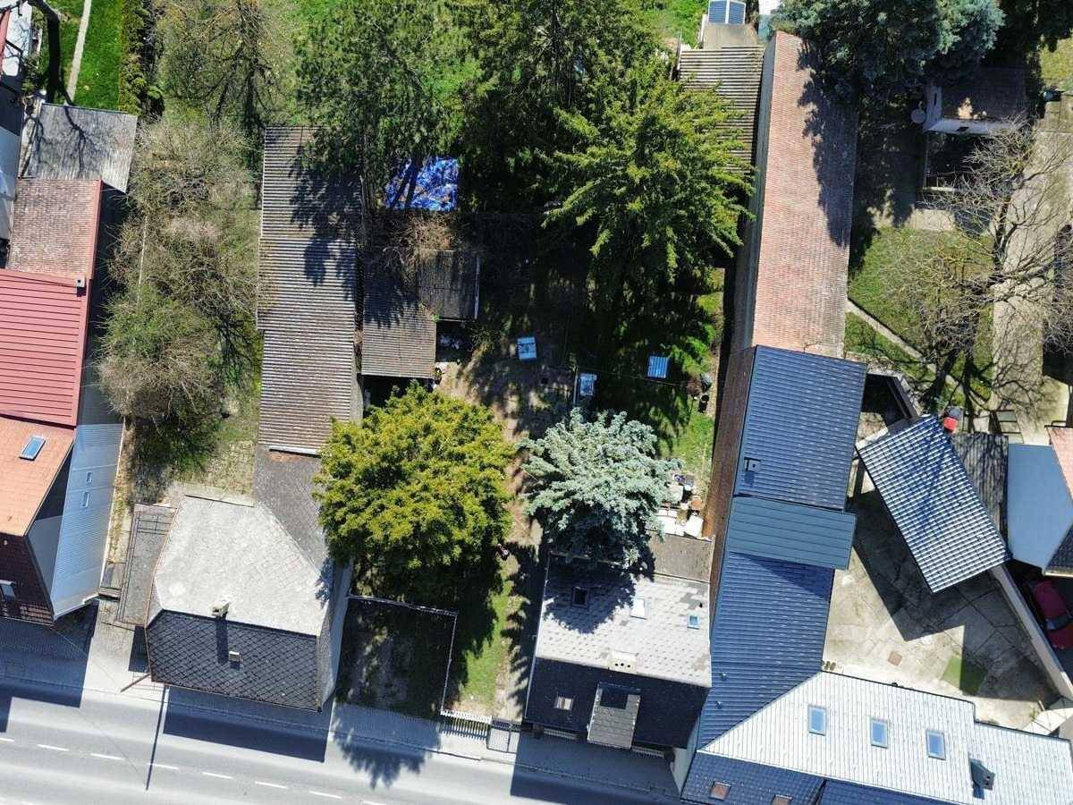 Draufsicht auf mehrere Häuser und Gärten entlang einer Straße mit verschiedenen Dachtypen.