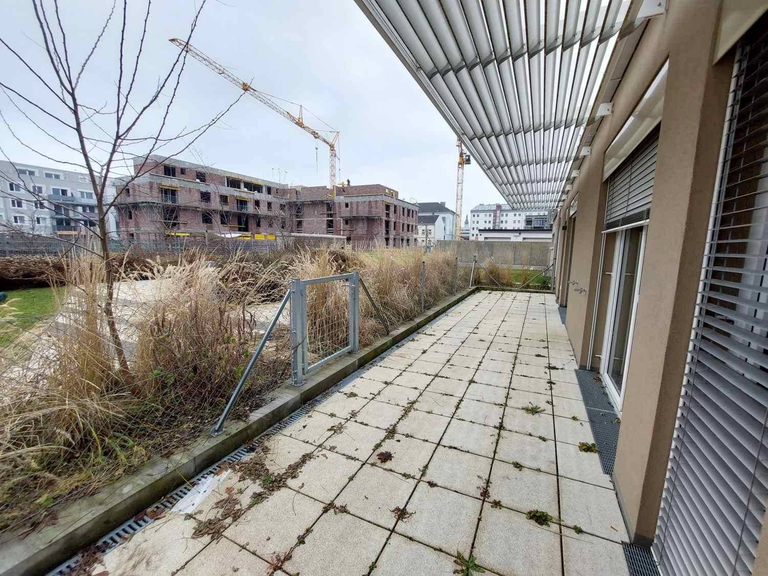 Weitläufige Terrasse mit Plattenboden und Blick auf die umliegenden Neubauten und Baustellenkräne.