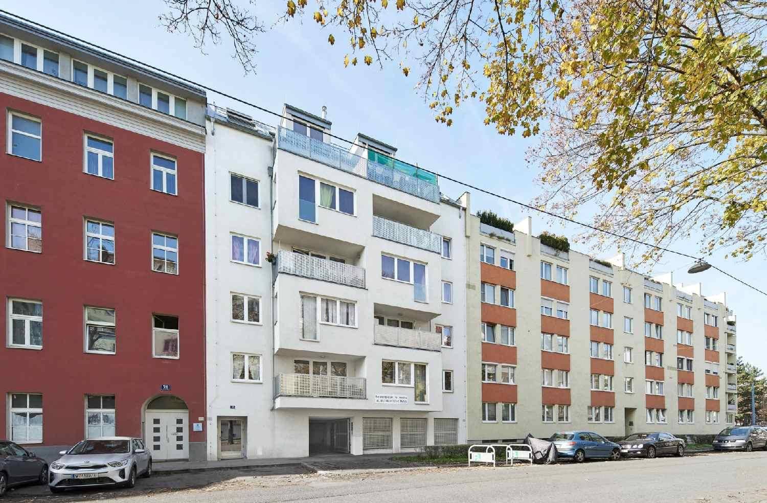 Ansicht der modernen Wohnhausfassade von der Straße mit Balkonen und großen Fenstern.