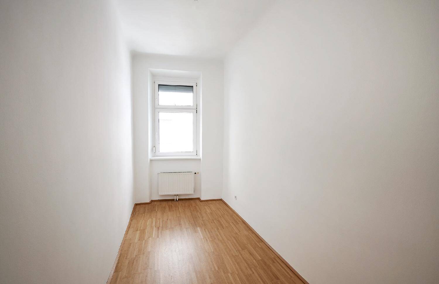 Kleines, helles Zimmer mit Parkettboden und einem Fenster, ideal als Schlaf- oder Arbeitszimmer.