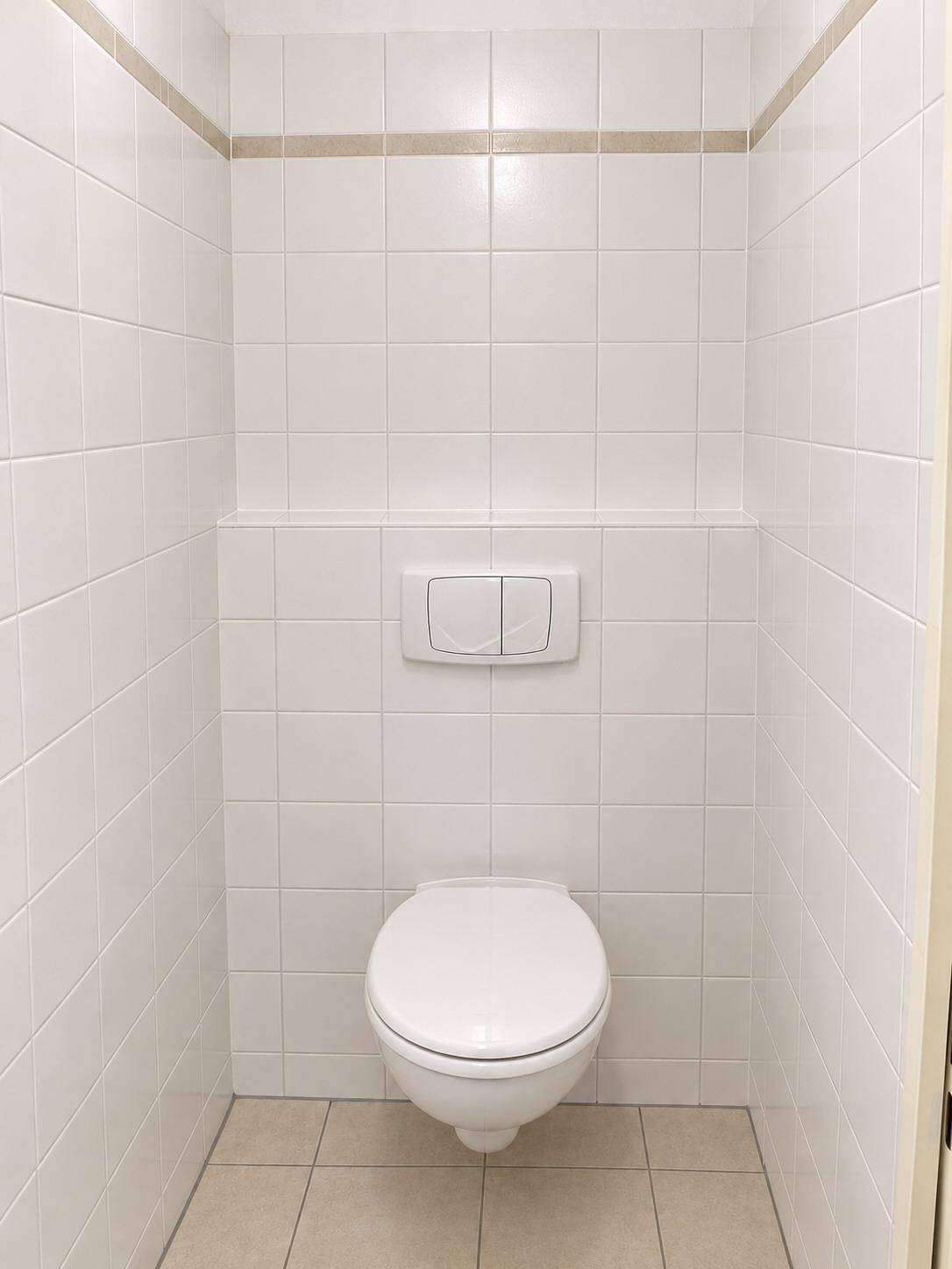 Separates WC mit wandhängender Toilette und weißen Fliesen, sauber und funktional.
