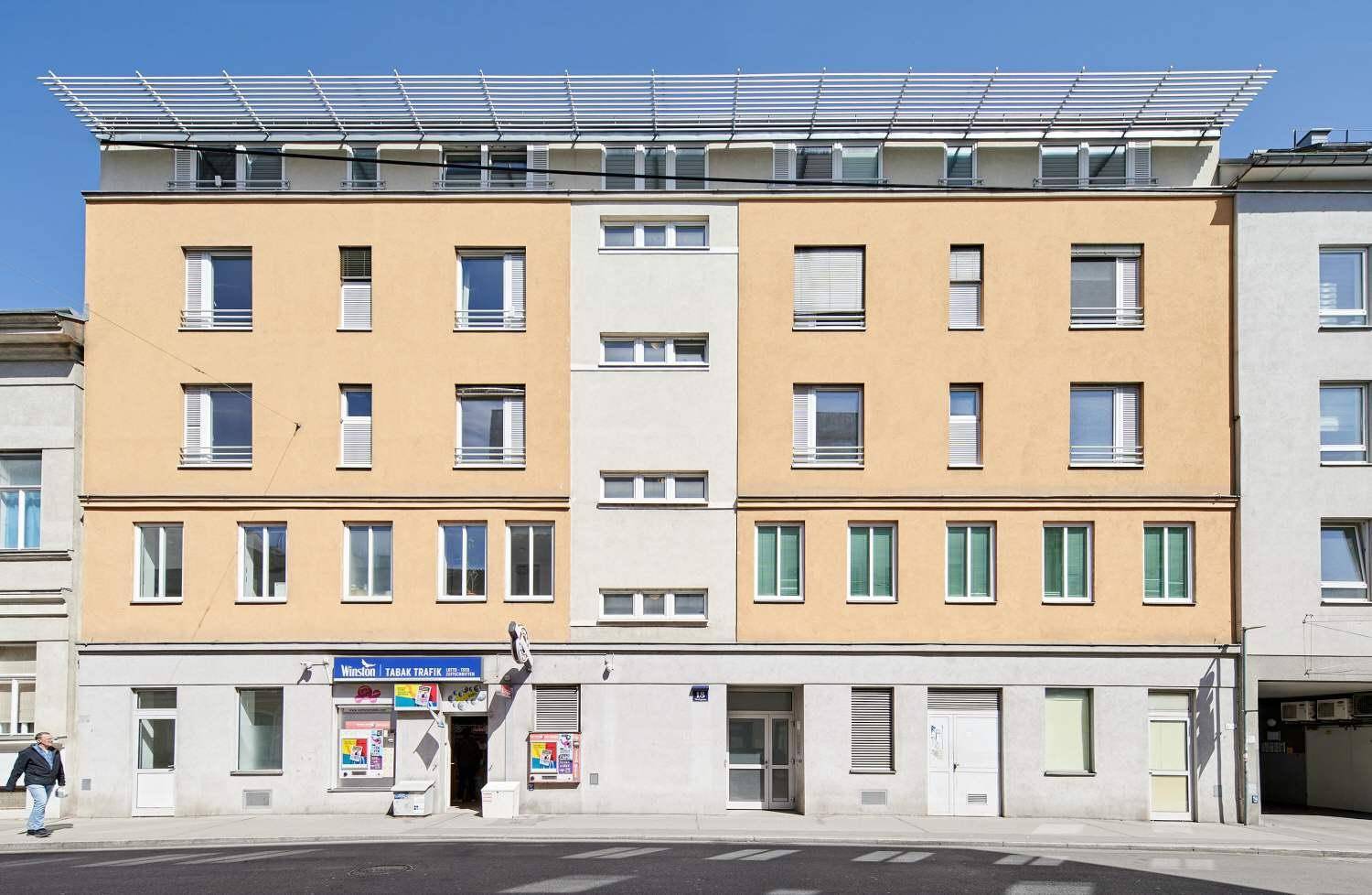 Mehrstöckiges Wohngebäude mit heller Fassade und vielen Fenstern.