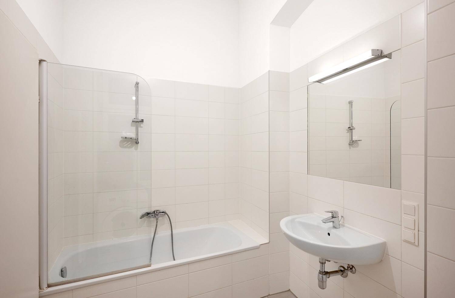 Modernes Badezimmer mit Badewanne, Duschwand und Waschbecken.