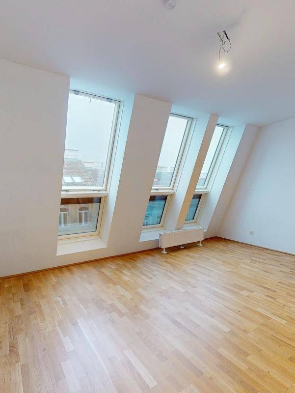 Heller Wohnraum im Dachgeschoss mit Holzboden und drei großen Dachfenstern.