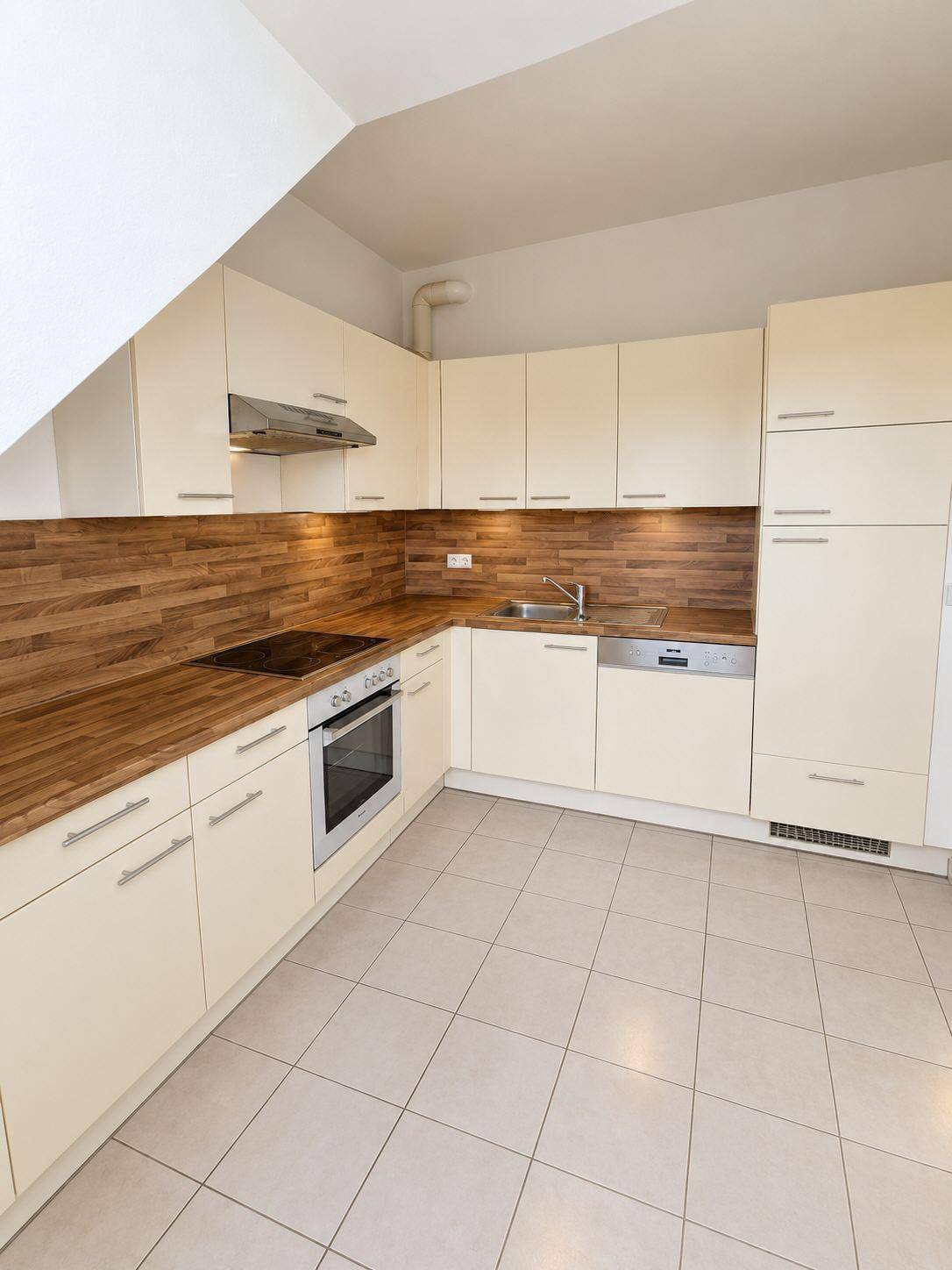 Voll ausgestattete Küche mit beigen Schränken, Holzdetails und integrierten modernen Geräten.