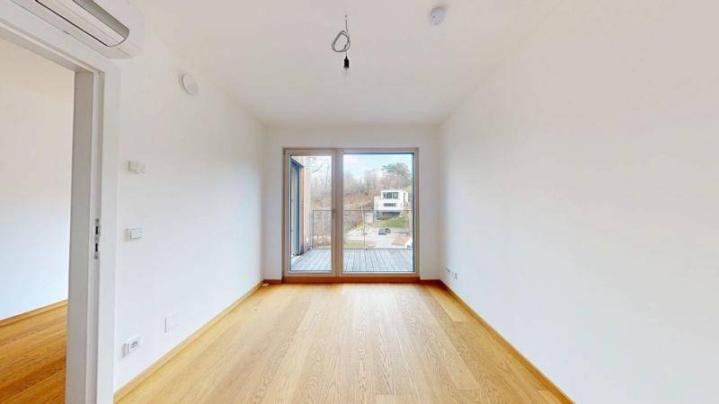 Helles Schlafzimmer mit Eichenparkettboden und Zugang zu einem Balkon mit Aussicht.
