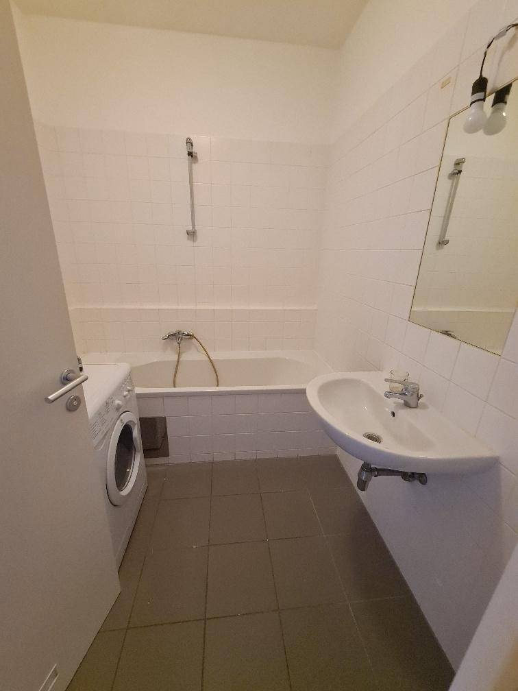 Gefliestes Badezimmer mit Badewanne, Waschbecken und Waschmaschine.