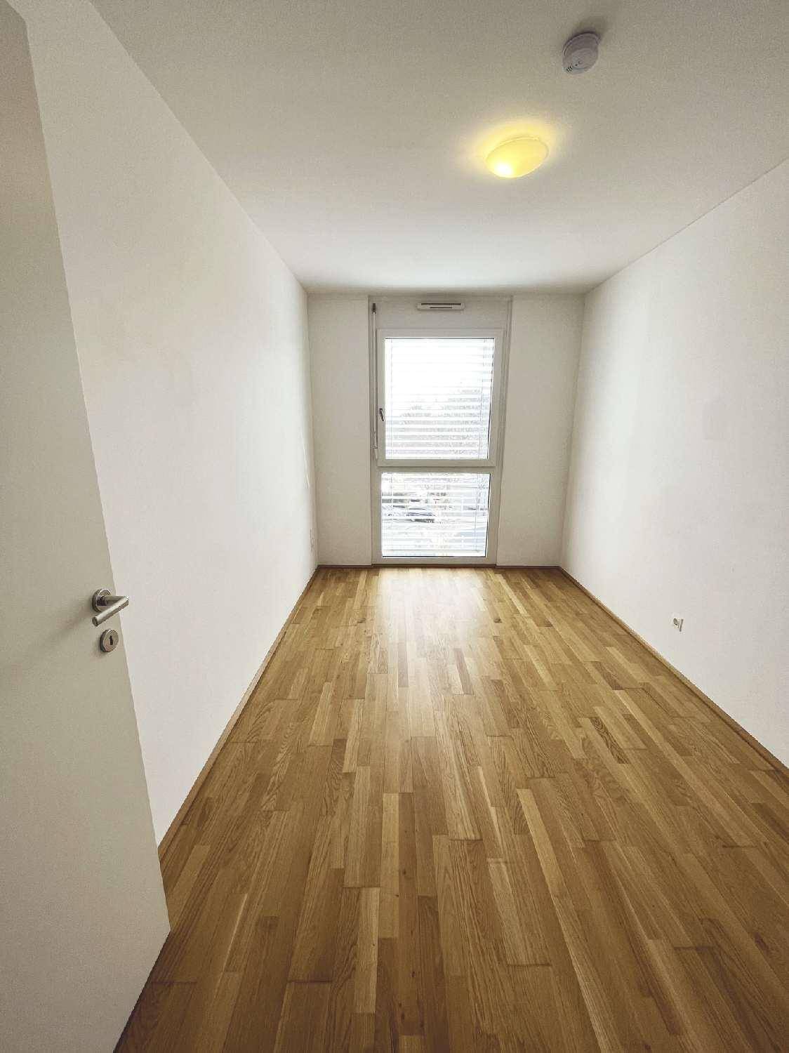 Helles Zimmer mit Parkettboden und einem großen Fenster, ideal als Schlafzimmer.