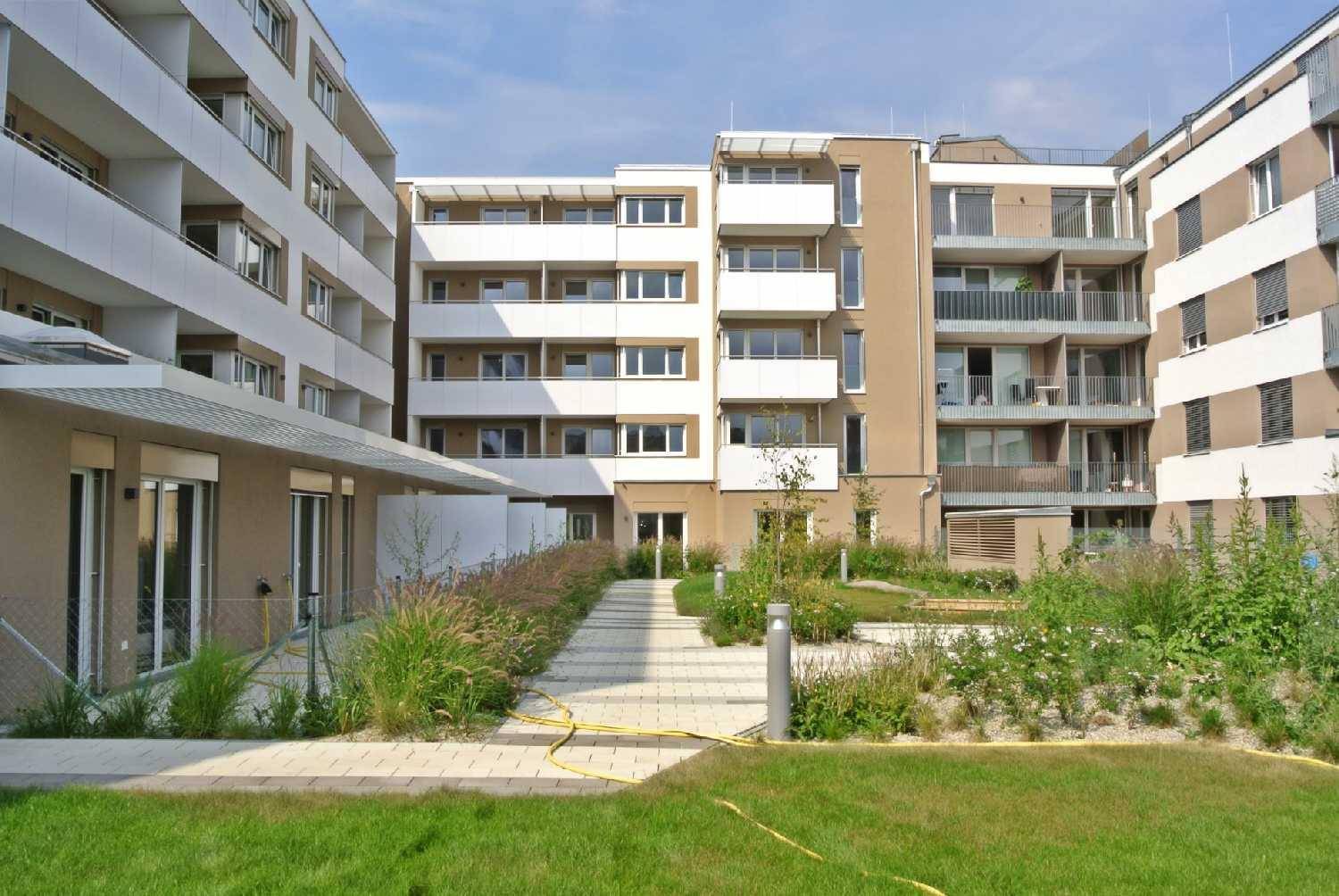 Moderne Wohnanlage mit gepflegten Grünflächen und Wegen zwischen den Gebäuden.