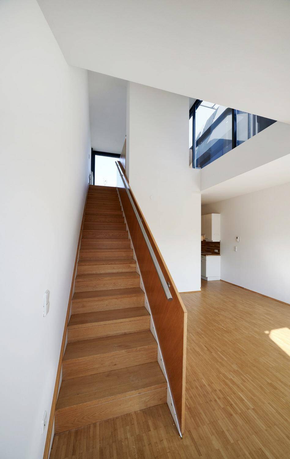 Helle Holztreppe mit modernem Geländer, die verschiedene Ebenen des Wohnraums verbindet.