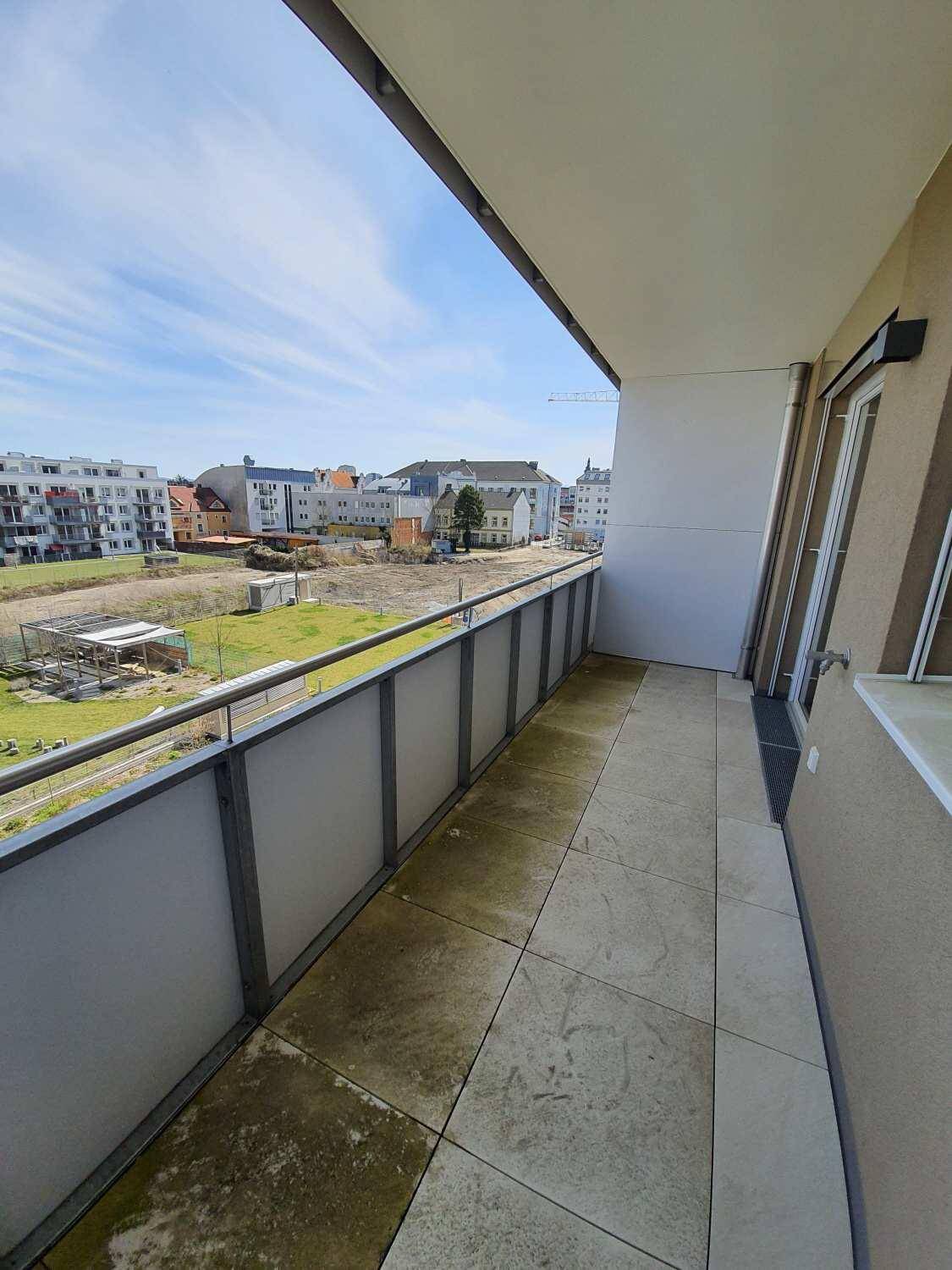 Geräumiger Balkon mit Fliesenboden und weitem Blick über die städtische Umgebung und Baustellen.