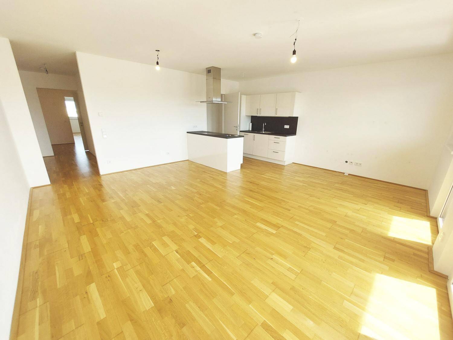 Geräumiger Wohn-Essbereich mit offener Küche, Parkettboden und viel Tageslicht.