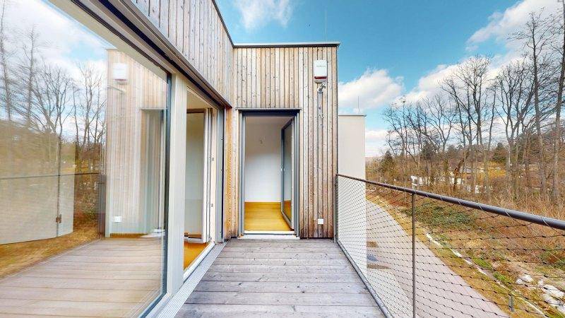 Geräumiger Holzbalkon mit Metallgeländer und weitem Blick in die grüne Umgebung.