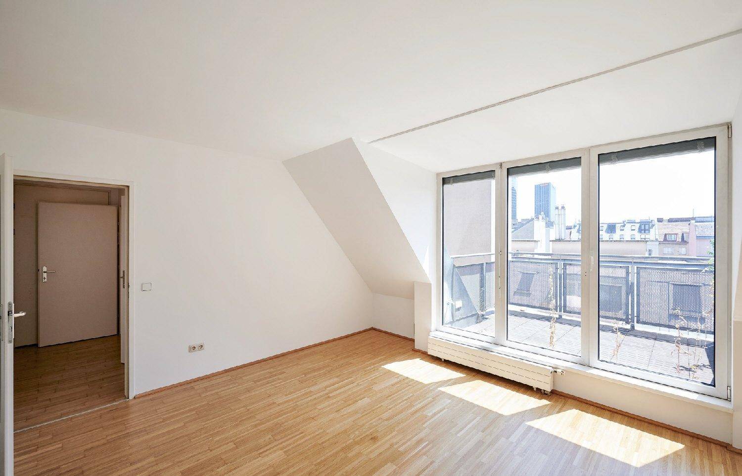 Geräumiges Zimmer im Dachgeschoss mit Holzboden, schrägen Wänden und viel Tageslicht.