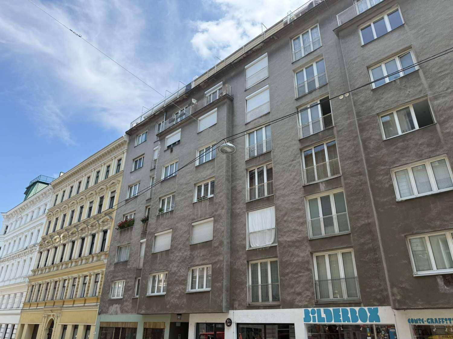Graues Mehrfamilienhaus mit zahlreichen Fenstern und einer schlichten Fassadengestaltung.